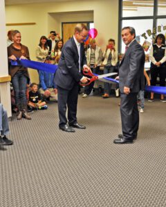 Loren Bough, chair of the Big Sky School District Board of Trustees and holding the giant scissors, along with BSSD Superintendent Dustin Shipman cuts the ceremonial ribbon to open the new Ophir Elementary School on Sept. 5. PHOTO BY THERESA DA SILVA 