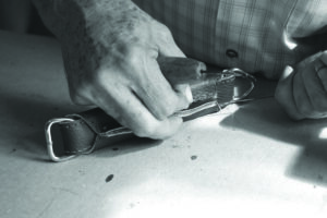 Adam Mochorro hand stitches a briefcase handle. PHOTO BY JAMES K. SANDERSON