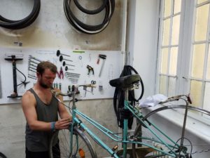 Experienced volunteer Jakob Schult fixes the front brake of a cruiser bike on June 6, 2016. Schult is in charge of developing Rückenwind’s new app.