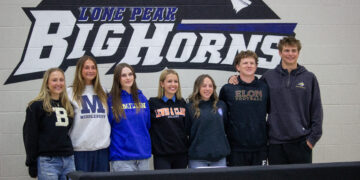 Seven students pose in front of a Lone Peak Big Horns mural at school.