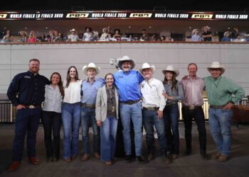 Group of people in cowboy hats and western attire posing together on a stage at a World Finals event.