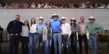 Group of people in cowboy hats and western attire posing together on a stage at a World Finals event.