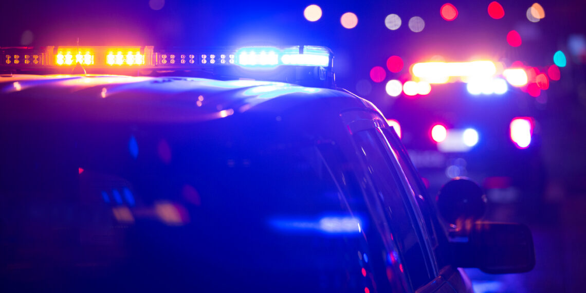 Police car on a dark street with blue and red emergency lights flashing.
