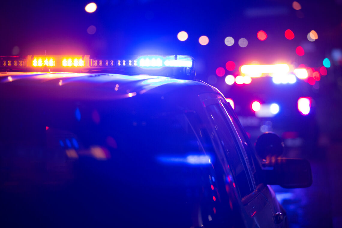 Police car on a dark street with blue and red emergency lights flashing.
