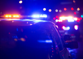 Police car on a dark street with blue and red emergency lights flashing.