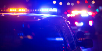 Police car on a dark street with blue and red emergency lights flashing.