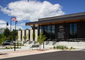 Exterior view of Gallatin County Justice Center with American and state flags, glass entrance, and landscaped plaza.