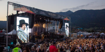 Outdoor concert at Wildlands Festival with large stage, banners, and a crowded audience against mountain backdrop at dusk.